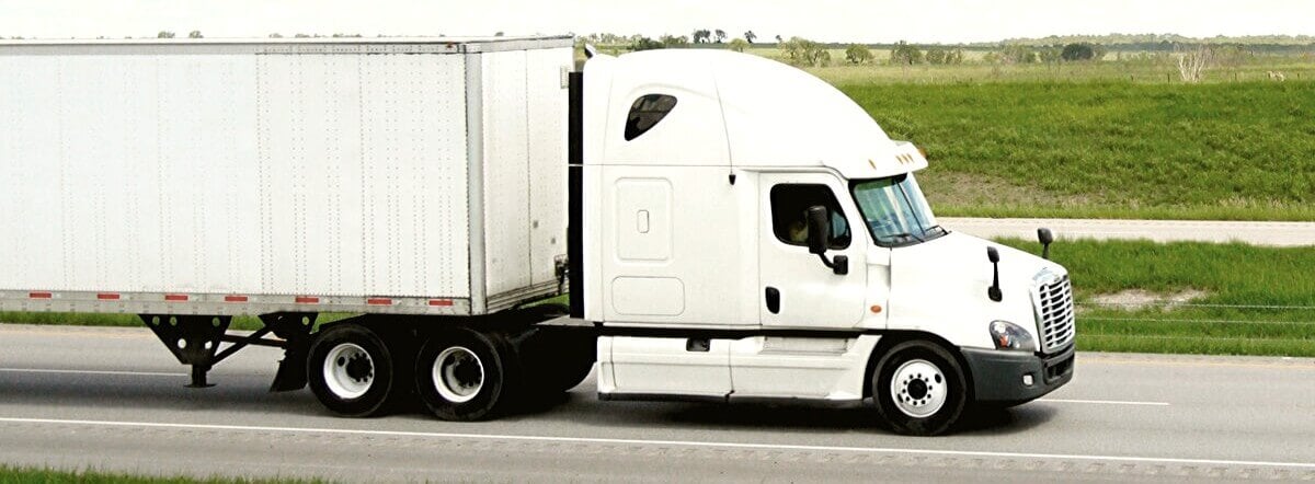 White semi truck traveling down an interstate.