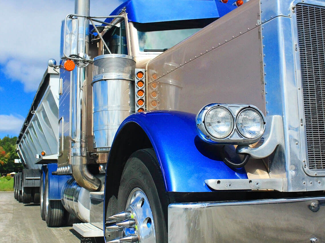 Blue semi truck and trailer in a parking lot.