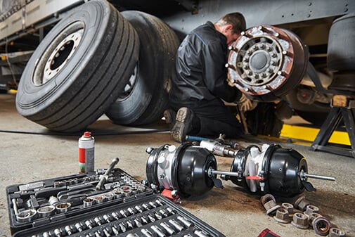 A mechanic replacing the brakes on a semi truck.