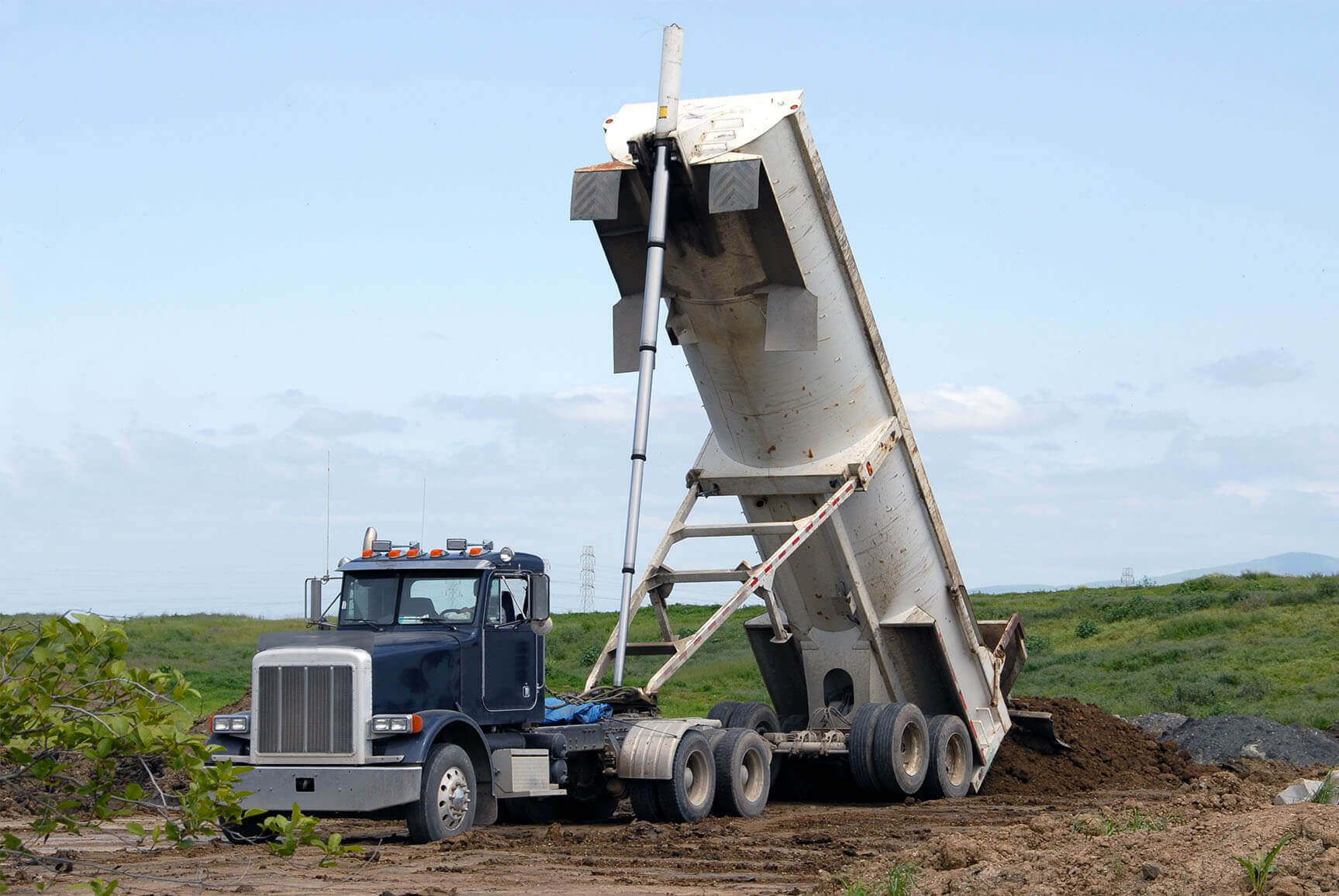 A semi emptying dirt out of an end dump trailer.