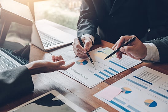 Three people looking at financial charts.